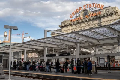 Line of passengers outdoors at Union Station in Denver, Colorado with vintage Union Station - Travel by Train sign in background.