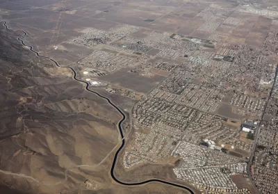 Aerial view of California Squeduct snaking past housing developments in the Mojave Desert
