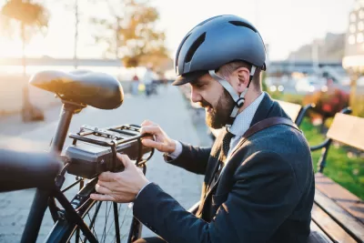 Young bearded man with helmet setting up battery on back of electric bike