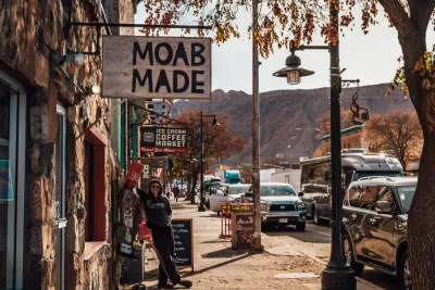 Person standing under sign that says "Moab Made" in downtown Moab, Utah.