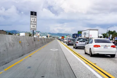 Empty carpool lane separated by yellow and black lines next to traffic on freeway in Southern California.