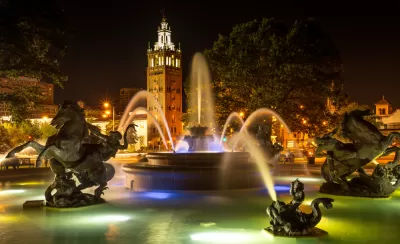 Nighttime shot of decorative fountain with horses and Country Club Plaza tower in background