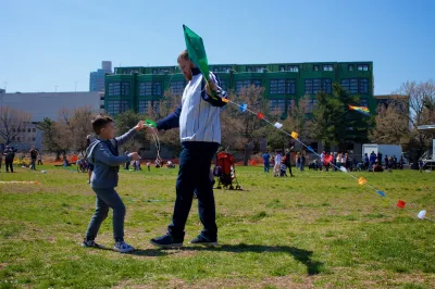 Child and adult man playing with kite in park in Philadelphia, Pennsylvania on a sunny day.