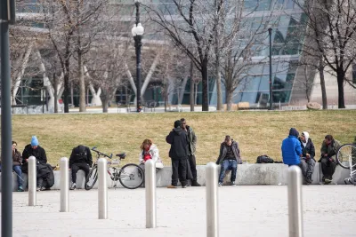 Unhoused people sitting on a concrete ledge in a public park in Salt Lake City, Utah.