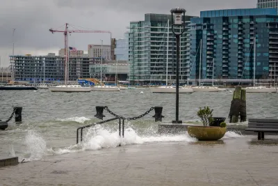 Waves splash over concrete dock in Boston harbor during a storm.