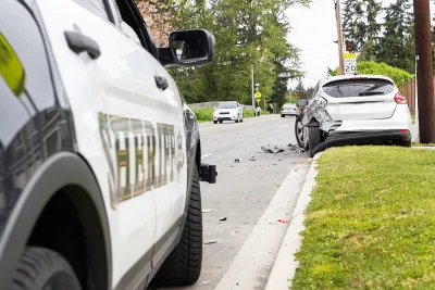 Close-up on Sheriff car parked next to grassy curb with silver car with damaged bumper stopped on grass immediately after crash.