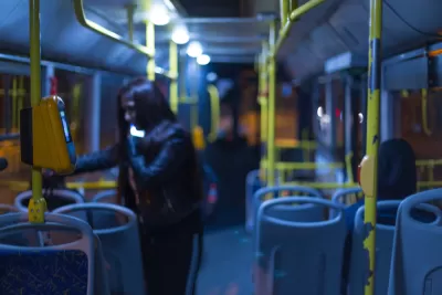 Nighttime bus interior with one rider standing by door