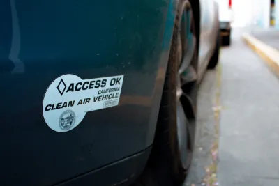 Close-up on "Access Ok" electric car sticker on back of dark colored car bumper.
