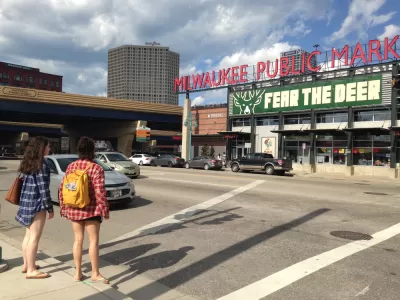 Two women waiting to cross street facing Milwaukee Public Market sign