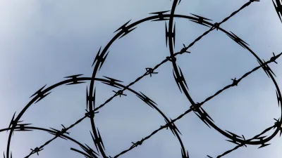 Close-up of razor wire at top of fence against blue sky.
