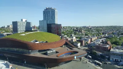 Aerial of Barclays Center stadium in New York Coty with green roof and modern towers behind it.