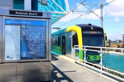 Yellow and black Los Angeles Metro light rail train stopped at Redondo Beach elevated outdoor station.