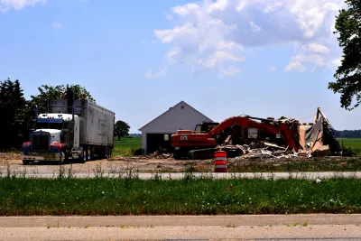 Small house in emmpty green frield being demolished to make way for road construction.