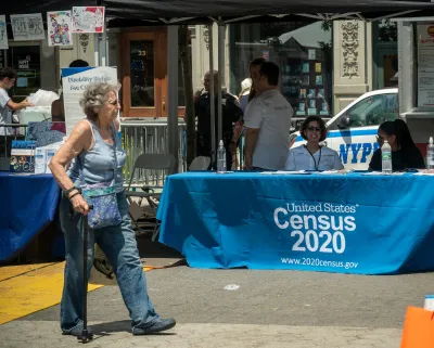 Two workers at U.S. Census 2020 booth on street.