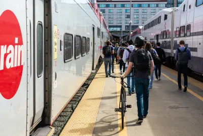 People walking bikes on Caltrain platform next to Caltrain bike car.