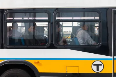 Close-up on MBTA bus window with passengers looking out from seats in Boston, MA.
