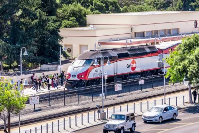 A Caltrain train picks up a large crowd of people at a station.