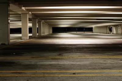 Empty parking garage at night with yellow lines marking spots and fluorescent lighting