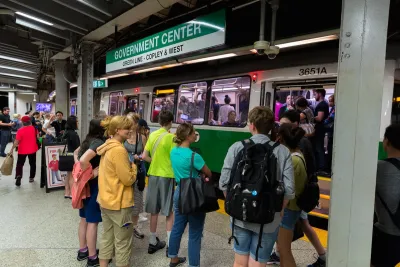 A crowd of people boarding Boston's green line in an underground subway station.