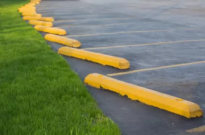 Parking lot with yellow concrete bars adjacent to green grass