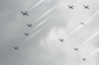 Against a cloudy sky, a group of planes cloud seed by spraying salt into the clouds.