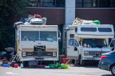 Two RVs used as homes by their residents surrounded by household items in parking lot in North Hollywood, California.