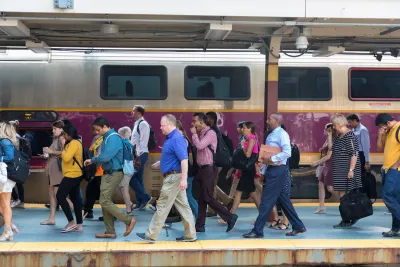 A group of people walk past Boston's purple commuter rail.