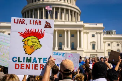 Protesters holding up anti-Trump climate protest signs in front of Capitol dome in Washington DC. 