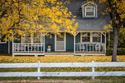 Grey traditional two-story house in Meridian, Idaho with trees with yellow fall leaves in front.