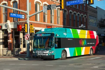 A colorful Via transit bus next to a brick building.