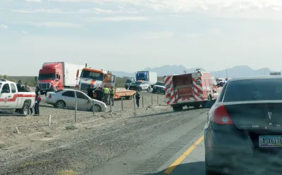 Cars crashed inthe middle of a dirt highway median.