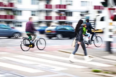 Pedestrians and cyclists in busy city crosswalk with blurred motion