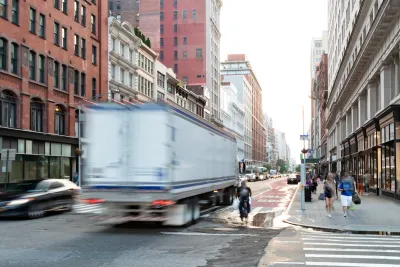 Blurred white truck driving down New York City street with blurred cyclist next to it.