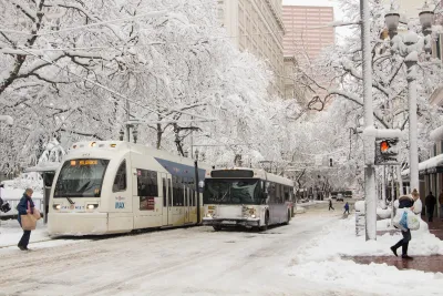 TriMet bus next to Max light rail train on snowy street in Portland, Oregon.