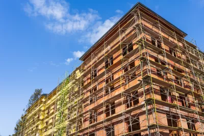Multistory wood frame apartment building under construction against blue sky