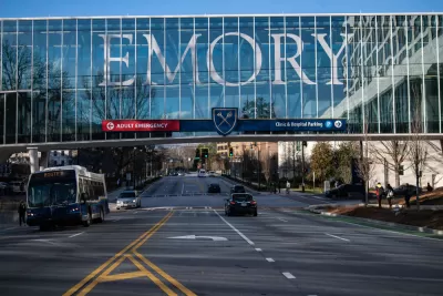 View of enclosed glass pedestrian bridge over street with EMORY in large letters across the glass
