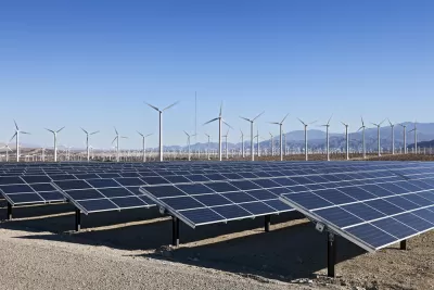 Solar array and wind turbines in California with mountains in background