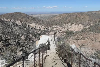 View of hiking trail descending into desert mountains with steps carved into stone and guardrails at Devil's Punchbowl Natural Area, Los Angeles County