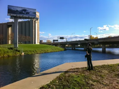Man standing on riverbank in Montreal holding up sound measuring equipment.