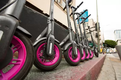 Low close-up shot of black and pink Lyft e-scooters lined up on downtown Los Angeles sidewalk