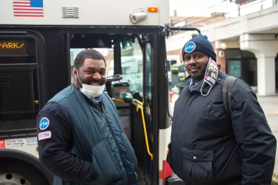 Two Chicago transit operators standing in front of a bus and smiling at the camera