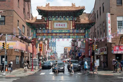Ornate Chinatown gate in Philadelphia, Pennsylvania with people walking in front of it.
