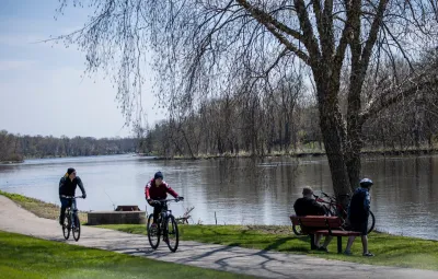 Two cyclists biking on paved trail past lake in Chicago, Illinois.