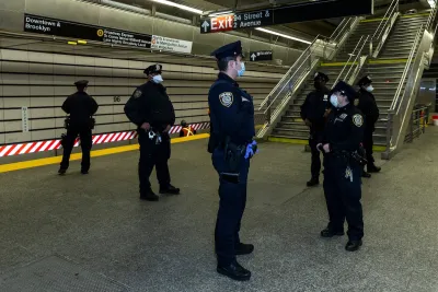 Group of NYC transit police officers stand in subway station wearing blue surgical masks.