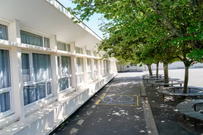 Schoolyard with leafy green trees surrounded by benches 