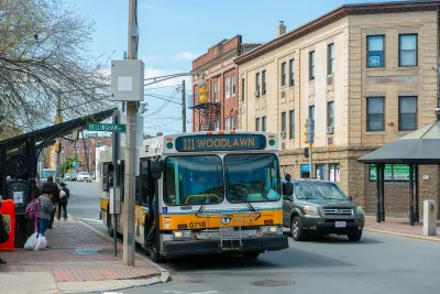 An MBTA bus picks up people from a bus stop.
