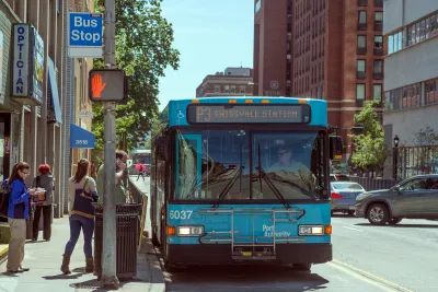 Blue Pittsburgh city bus stopped at a station on street.
