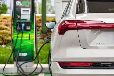 Close-up of back of white electric Audi SUV plugged into charging station