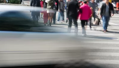 People in crosswalk with blurred fast car passing in foreground