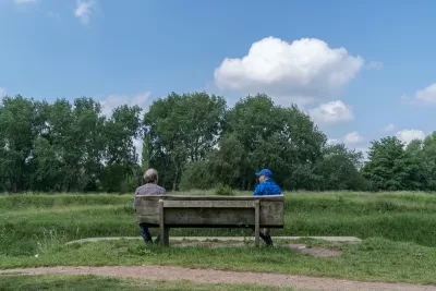 Two friends sit and talk at a social distance in Fletcher Moss park, Manchester, UK